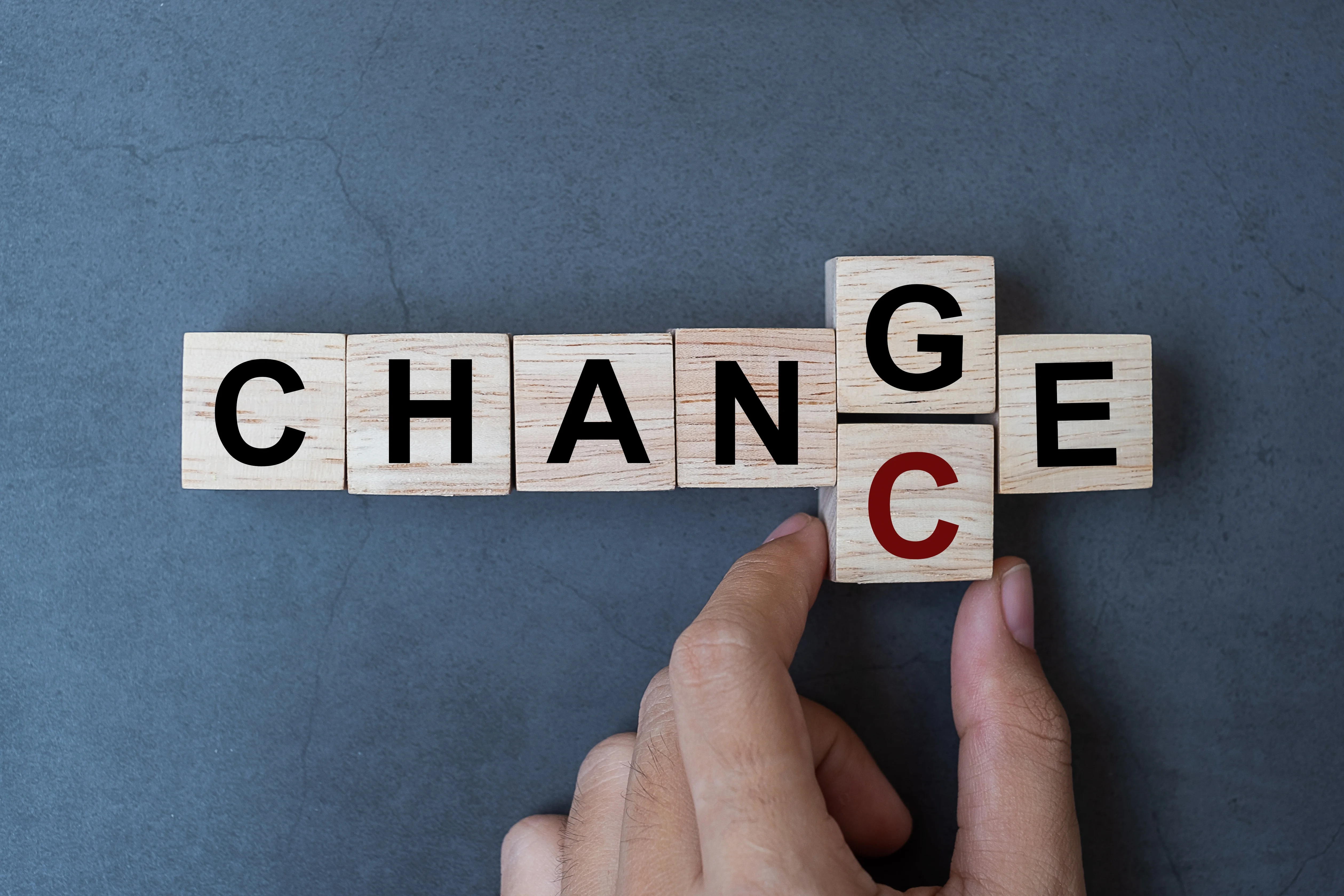 Hand changing wooden blocks from change to chance on gray background