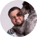 Man smiling while hugging a dog against a grey background.