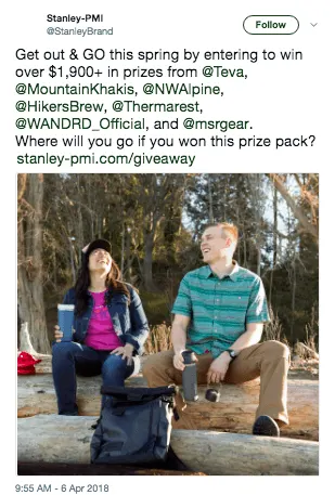 A couple enjoying a picnic in a spring forest with backpacks and mugs.