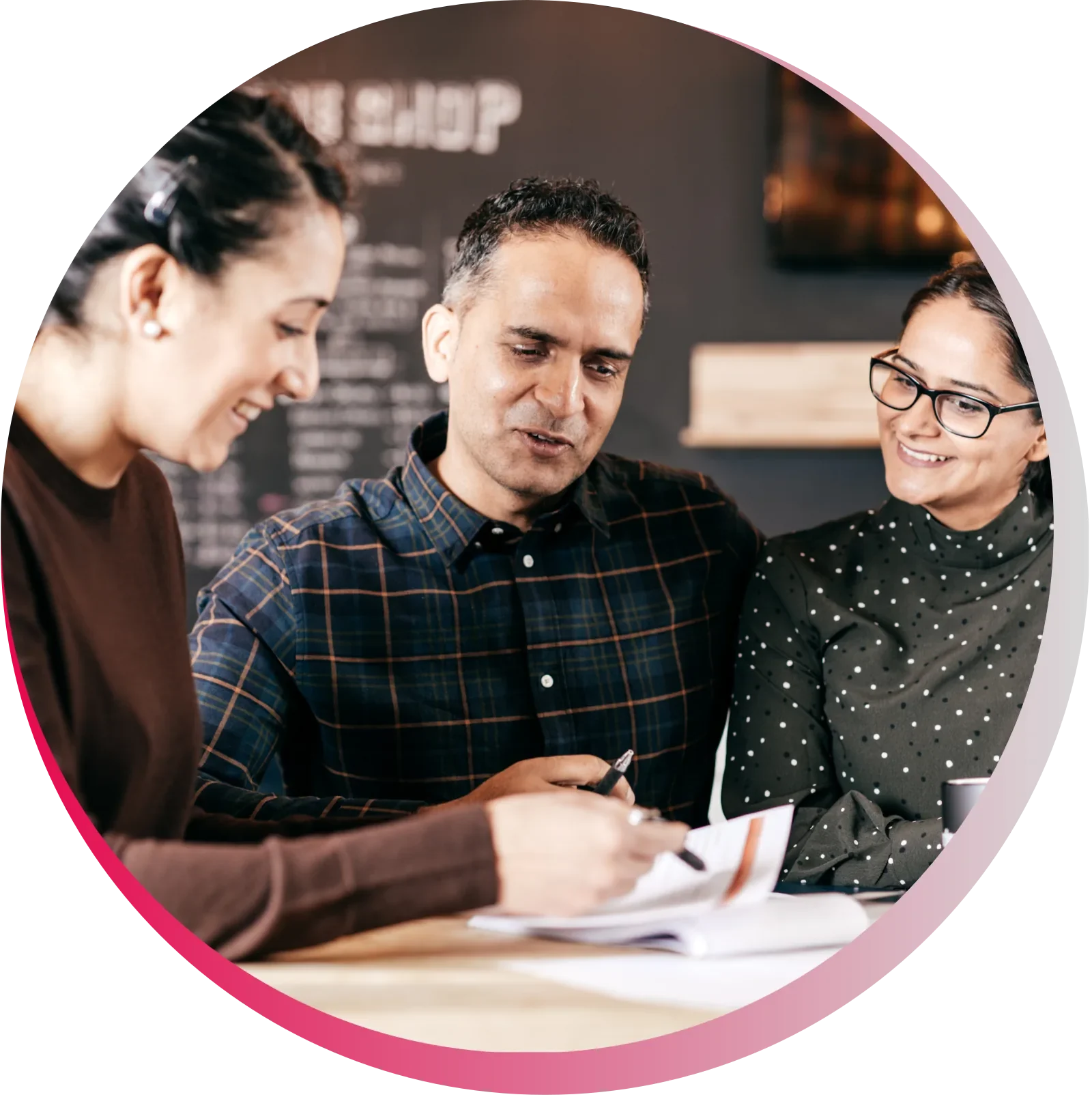 Three colleagues having a discussion at a cafe, reviewing documents.